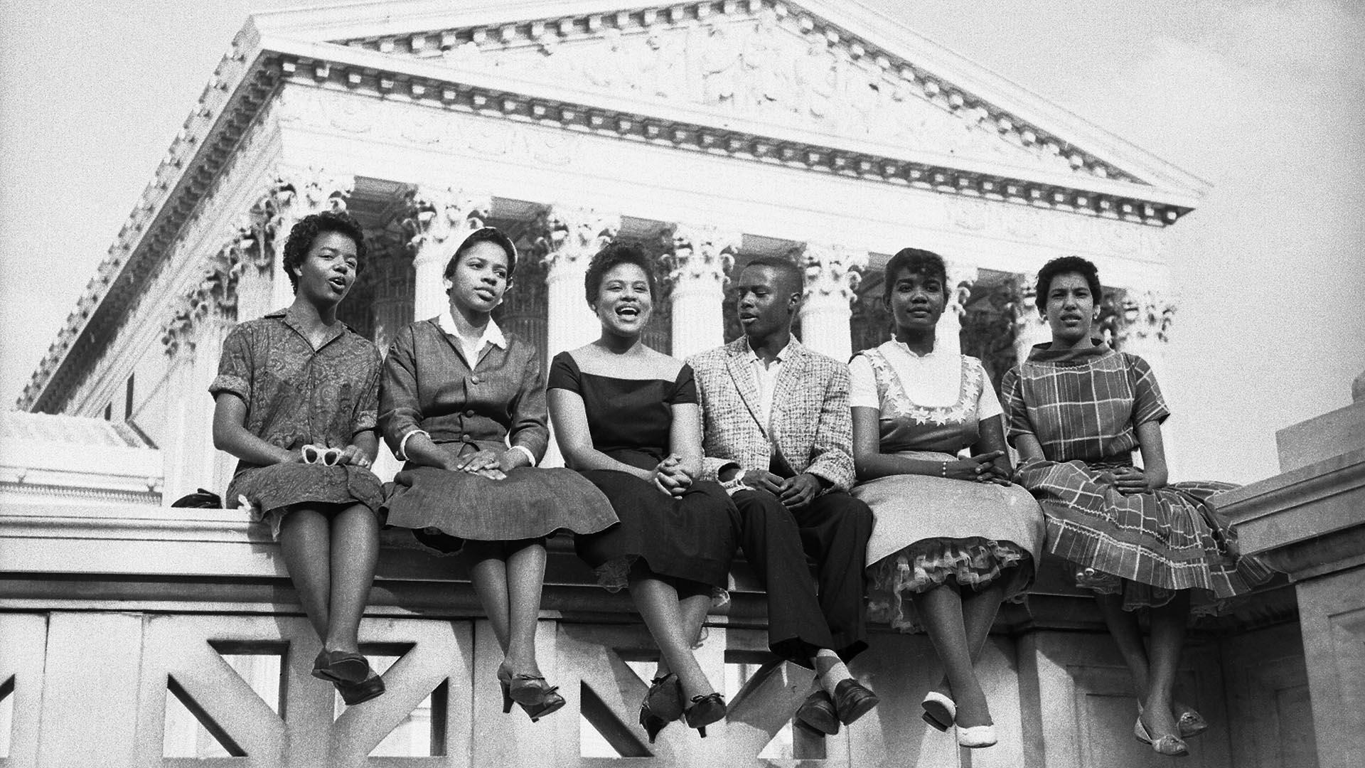Six Black children who attended Little Rock's Central High School sit outside the Supreme Court in this 1958 photo. 从左到右:卡洛塔墙, 15, 梅尔瓦Patillo, 16, 托马斯杰佛逊, 15, 米妮·简·布朗, 16, 格洛丽亚雷, 15, 伊丽莎白·埃德克福德, 16. 图片来源:Getty Images